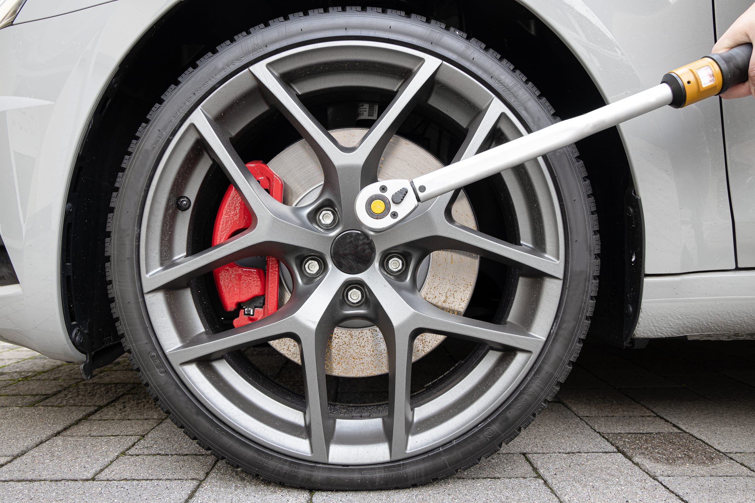 Alufelge mit rotem Bremssattel wird mit einem Drehmomentschlüssel am Fahrzeug festgezogen